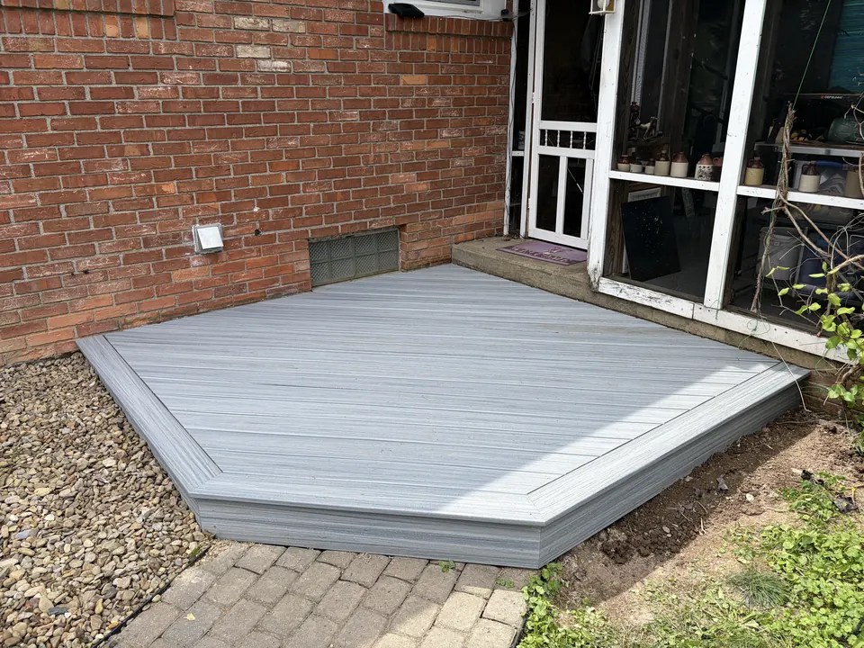 New grey composite deck stoop with a picture-frame border outside the brick home's screen porch